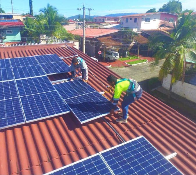 Técnicos de Solar Solution Savings instalando paneles solares en un techo residencial